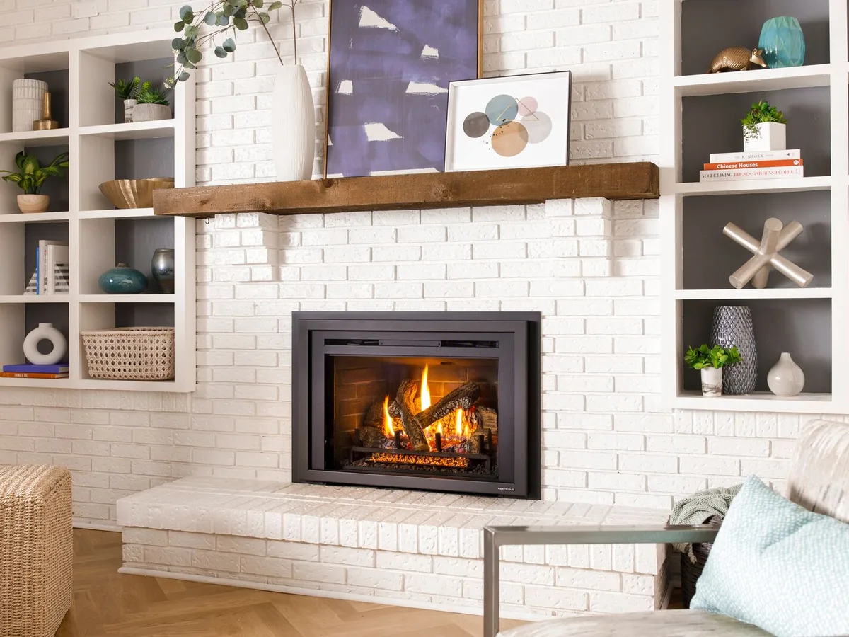 Heat & Glo gas insert burning inside a whitewashed brick fireplace with open shelving