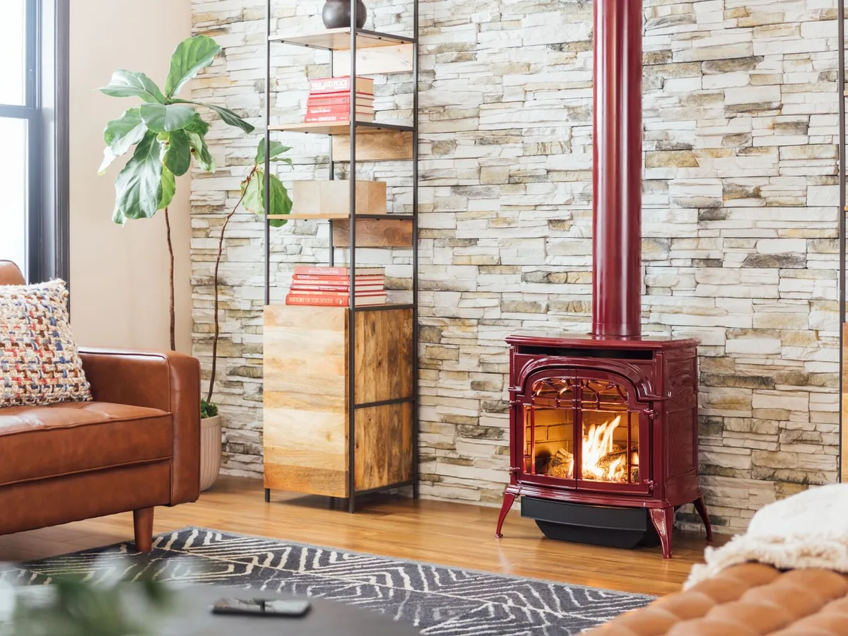 Quadra-Fire Stardance gas stove in red enamel against a stacked-stone wall