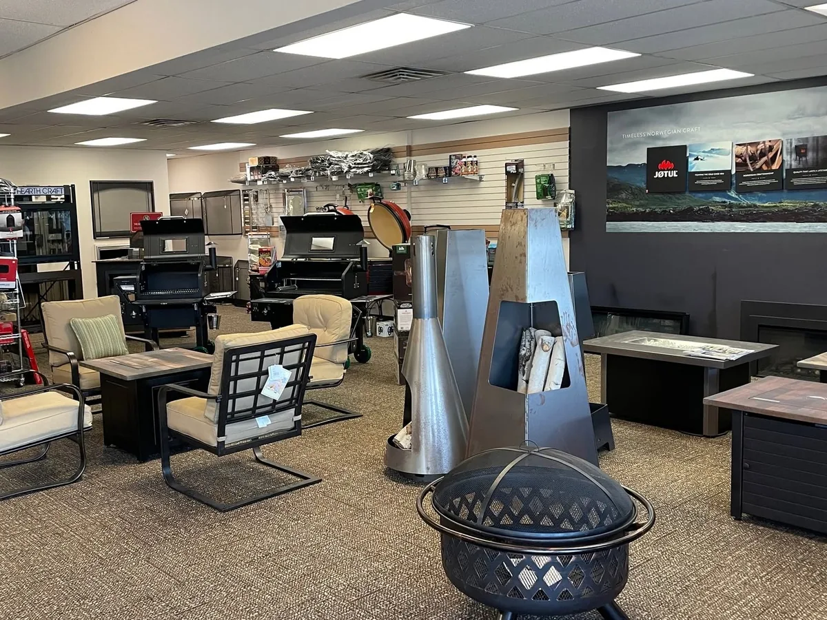 The Hearth & Home of Central New York showroom floor in East Syracuse: pellet grills, a Kamado, fire-pit tables, and the Jøtul display wall