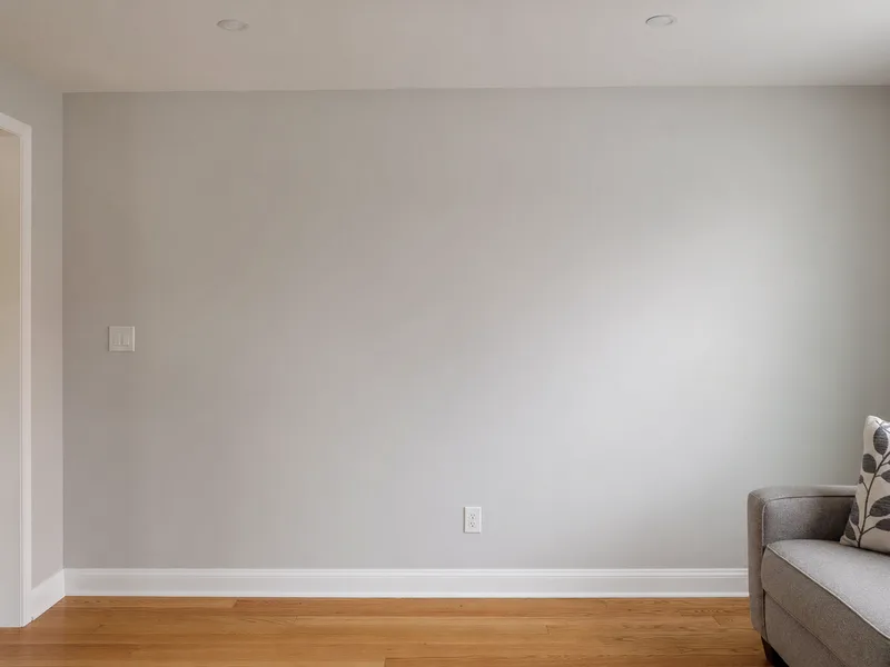An empty painted living-room wall with oak floor and baseboard, ready for a fireplace